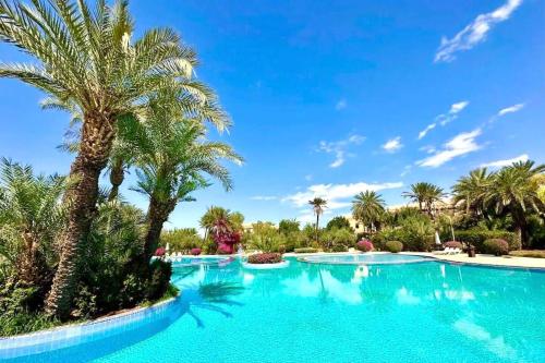a swimming pool with palm trees in a resort at Appartement standing piscine la palmeraie in Marrakech