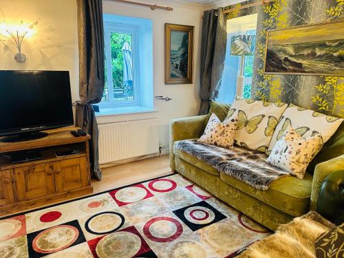 a living room with a couch and a television at Bay View Cottage in St Austell