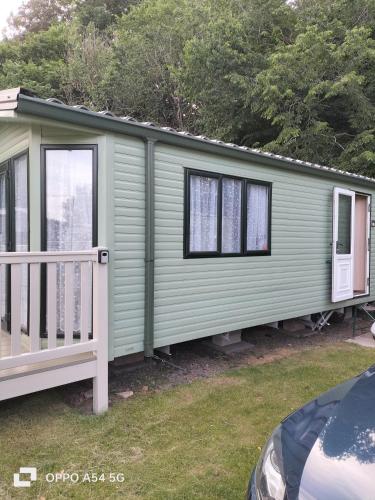 a green mobile home with a porch and a fence at Riverside leisure park Cheviot view in Wooler