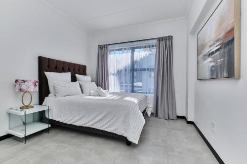 ein Schlafzimmer mit einem großen Bett und einem Fenster in der Unterkunft Fourways Luxe Haven, 6mins to Montecasino in Sandton