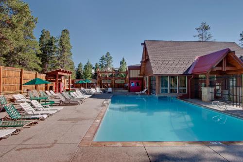 a swimming pool with lounge chairs and a house at Pine Ridge Condos in Breckenridge
