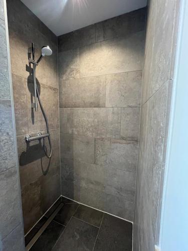 a shower in a bathroom with a stone wall at Duinpoort Appartement in Castricum