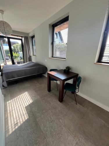 a bedroom with a bed and a desk and a table at Duinpoort Appartement in Castricum