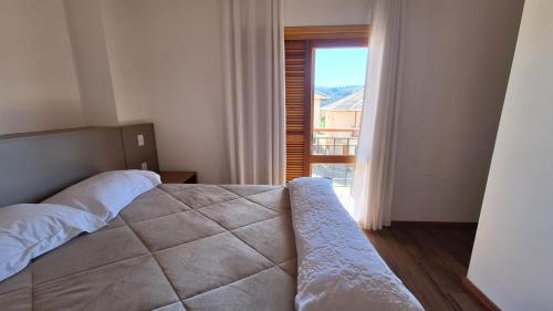 a bedroom with a bed and a large window at Chalé Coração de Monte Verde in Monte Verde