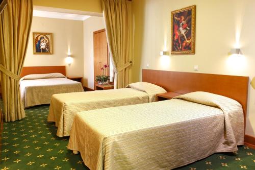 2 camas en una habitación de hotel con cortinas amarillas en Domus Pacis Fatima Hotel, en Fátima