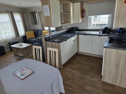 a small kitchen and living room with a table in it at PALM GROVE THE NeW PG68 3 BEDROOM CARAVAN CHAPEL ST LEONARDS in Chapel Saint Leonards