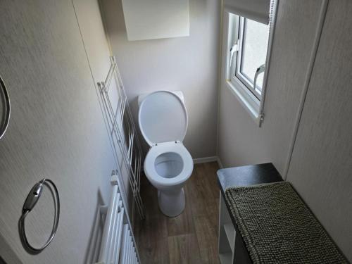 a small bathroom with a toilet and a window at PALM GROVE THE NeW PG68 3 BEDROOM CARAVAN CHAPEL ST LEONARDS in Chapel Saint Leonards