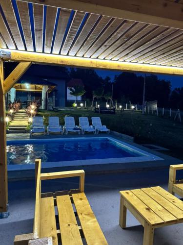 a swimming pool with chairs and a table and a bench at House_Zoi in Čelinac