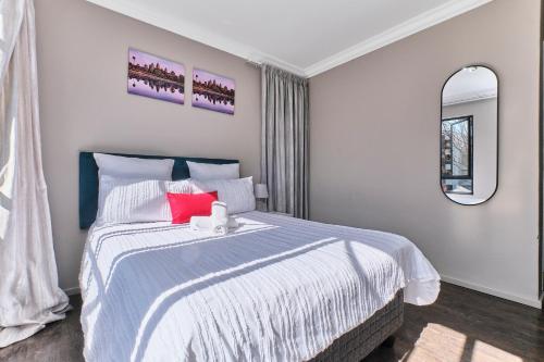a bedroom with a large bed with a red pillow at Luxury & Secure apartment - Fourways in Sandton
