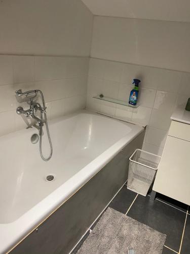 une baignoire blanche dans une salle de bain avec une bouteille de savon dans l'établissement Maison calme en campagne, à Archingeay