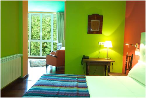 a bedroom with green walls and a bed and a window at Hotel Ibaiondo in Olave