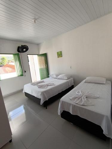 two beds in a room with white walls at hospedagem dos viajantes in Lençóis