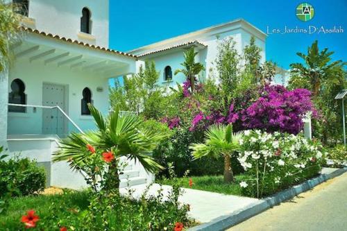ein Haus mit Blumen und Pflanzen davor in der Unterkunft Les Jardins d'Assilah in Asilah