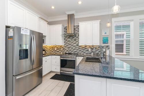 a kitchen with white cabinets and a stainless steel refrigerator at Two if by Sea in Mexico Beach