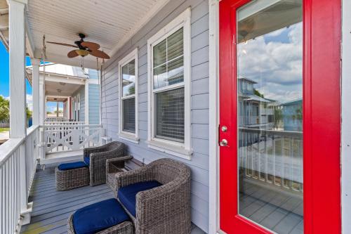 a front porch with wicker chairs and a red door at Two if by Sea in Mexico Beach