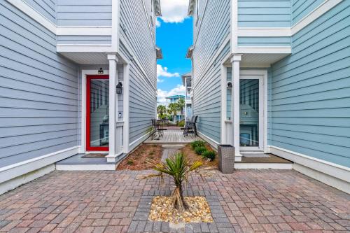 a building with a red door and a palm tree in a courtyard at Two if by Sea in Mexico Beach
