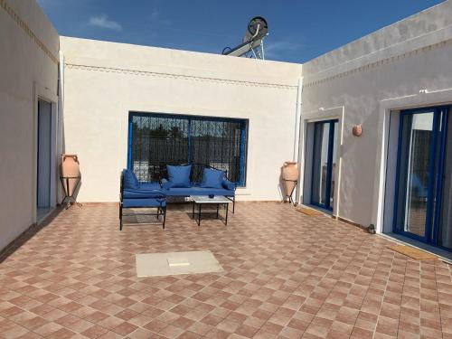 a patio with blue chairs and a table and windows at Dar Asteroth in El Guecheïne