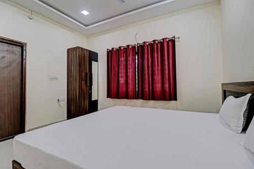 a bedroom with a white bed and red curtains at Super HOTEL O MIDWAY TREAT DHAR in Dhār