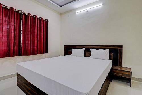 a bedroom with a large white bed with red curtains at Super HOTEL O MIDWAY TREAT DHAR in Dhār