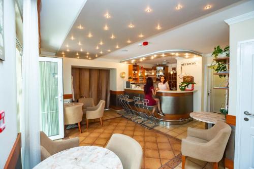 um restaurante com um bar com cadeiras e mesas em Hotel Pávai em Hajdúszoboszló