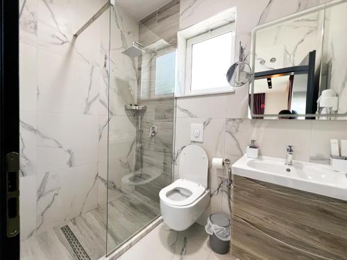 a bathroom with a toilet and a shower and a sink at Jata Hotel in Tirana
