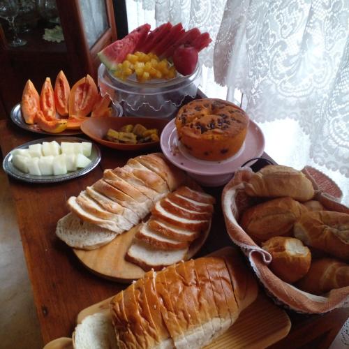 a table topped with different types of bread and pastries at Pousada Sítio Rústicu's in Domingos Martins