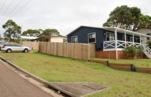 a house with a fence and a car parked in a yard at BeachBreaksManyana in Manyana