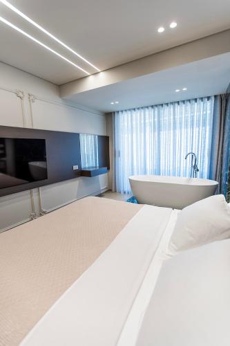 a bedroom with a large bed and a bath tub at Keslin Premium Seaside Apartments in Vlorë