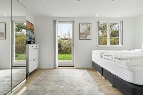 una camera da letto con un letto grande e finestre di Bright Summer House With Pool In Tisvildeleje a Tisvildeleje