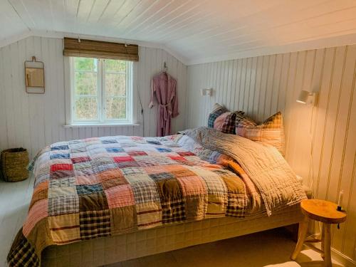 a bedroom with a bed with a quilt and a window at Idyllic House In A Lovely Hiking Area in Strömstad