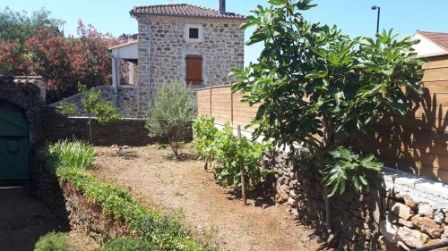 un jardin avec un mur en pierre et un bâtiment dans l'établissement Maison de caractère en pierre, à Laurac-en-Vivarais