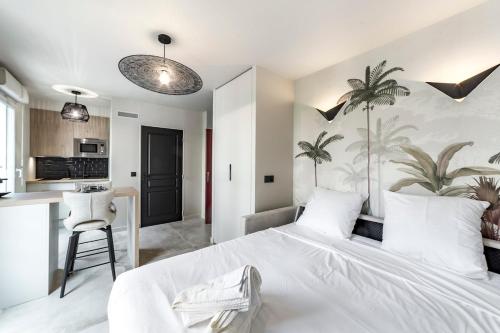 une chambre avec un grand lit blanc et une cuisine dans l'établissement Studio Madison Valmy, à Lyon