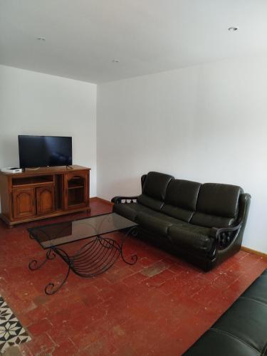 un canapé en cuir noir assis dans un salon avec une télévision dans l'établissement Les Meublés de la Motte Obin, à Muncq-Nieurlet