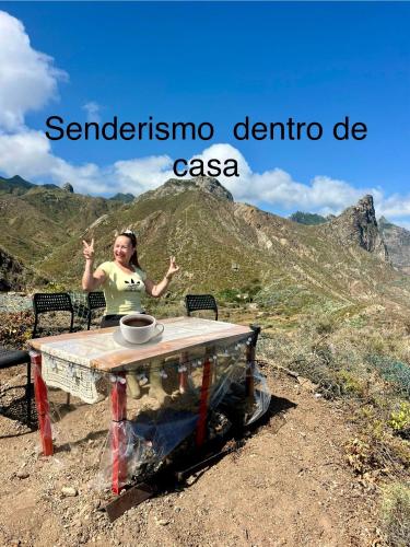 a woman sitting at a table in front of a mountain at Apartamento torres in Santa Cruz de Tenerife