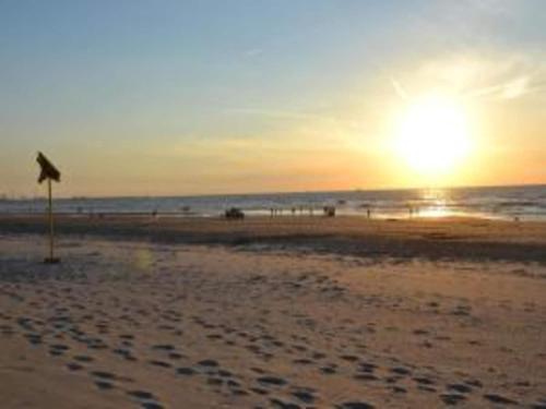 a sunset on a beach with footprints in the sand at Bungalow in Netherlands with Ship-Like Design in 's-Gravenzande
