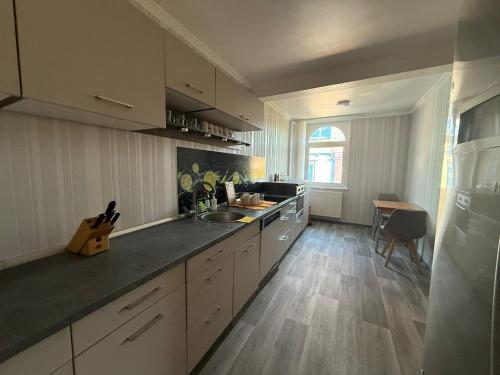 a kitchen with white cabinets and a sink and a table at Ferienwohnung Stadtmitte Bad Brückenau in Bad Brückenau