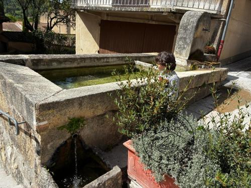 a woman is sitting next to a water fountain at Le Nid des Sources in Montbrun-les-Bains