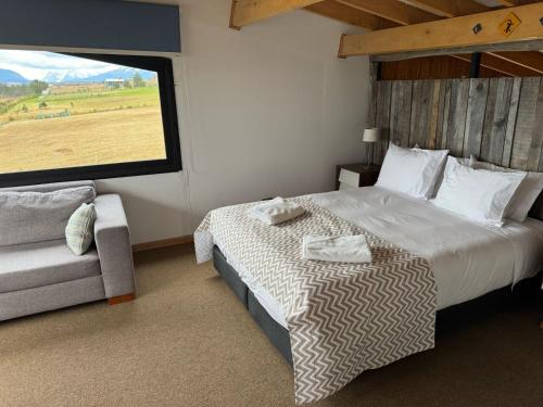 a bedroom with a bed and a couch and a large window at Casa Aoni in Puerto Natales