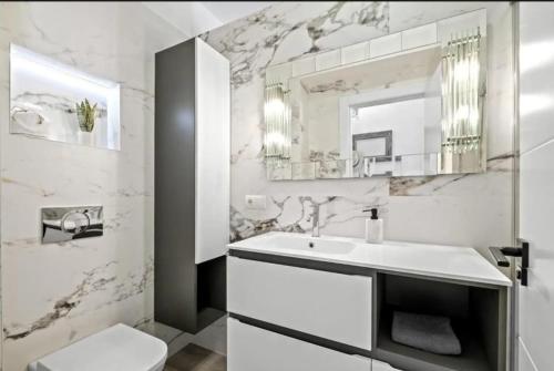 a white bathroom with a sink and a mirror at Spacious Malaga House with private walled-in yard in Málaga