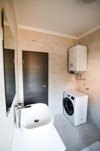 a bathroom with a toilet and a washing machine at Four Oaks Holiday House in Murvica