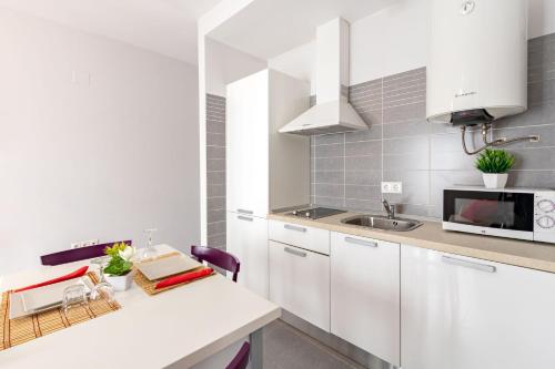 a white kitchen with a counter and a sink at YOKOI Ayamonte in Ayamonte
