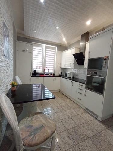 a kitchen with white cabinets and a table and chairs at Villa Varzob ll in Warsaw