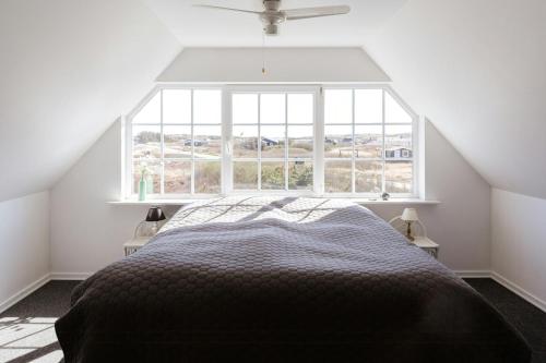 a bedroom with a bed and a large window at Atmosphere Close To Water Surrounded By Pines in Hvide Sande