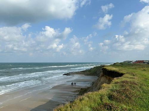 two people walking on a beach next to the ocean at Idyllic Holiday Home Charm In Nr, Lyngby in Løkken