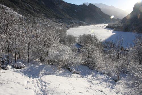 a snow covered valley with a river and trees at Hôtel Restaurant Gîtes Les 5 Saisons in Freissinieres