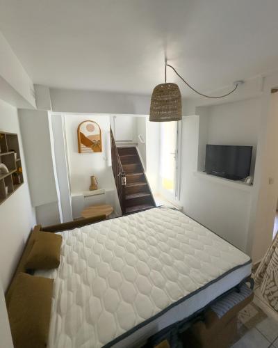 a room with a bed and a television and stairs at Évasion en bord de mer - T2 au coeur des calanques in Ensuès-la-Redonne