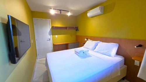 a bedroom with a white bed and a yellow wall at Flat na BeiraMar com Piscina Privativa in Porto De Galinhas