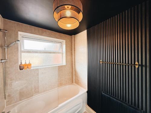 ウォリントンにあるBee Stays - Pickmere Houseのバスルーム(バスタブ、シャワー、シャンデリア付)