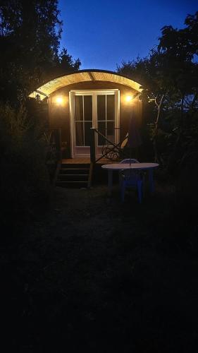 une petite maison avec une table devant elle la nuit dans l'établissement Magnifique roulotte, à Sospel