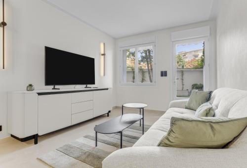 un salon blanc avec une télévision et un canapé dans l'établissement Modern 2 chambres avec jardin Martinez , 5 minutes from palais of festivals, à Cannes